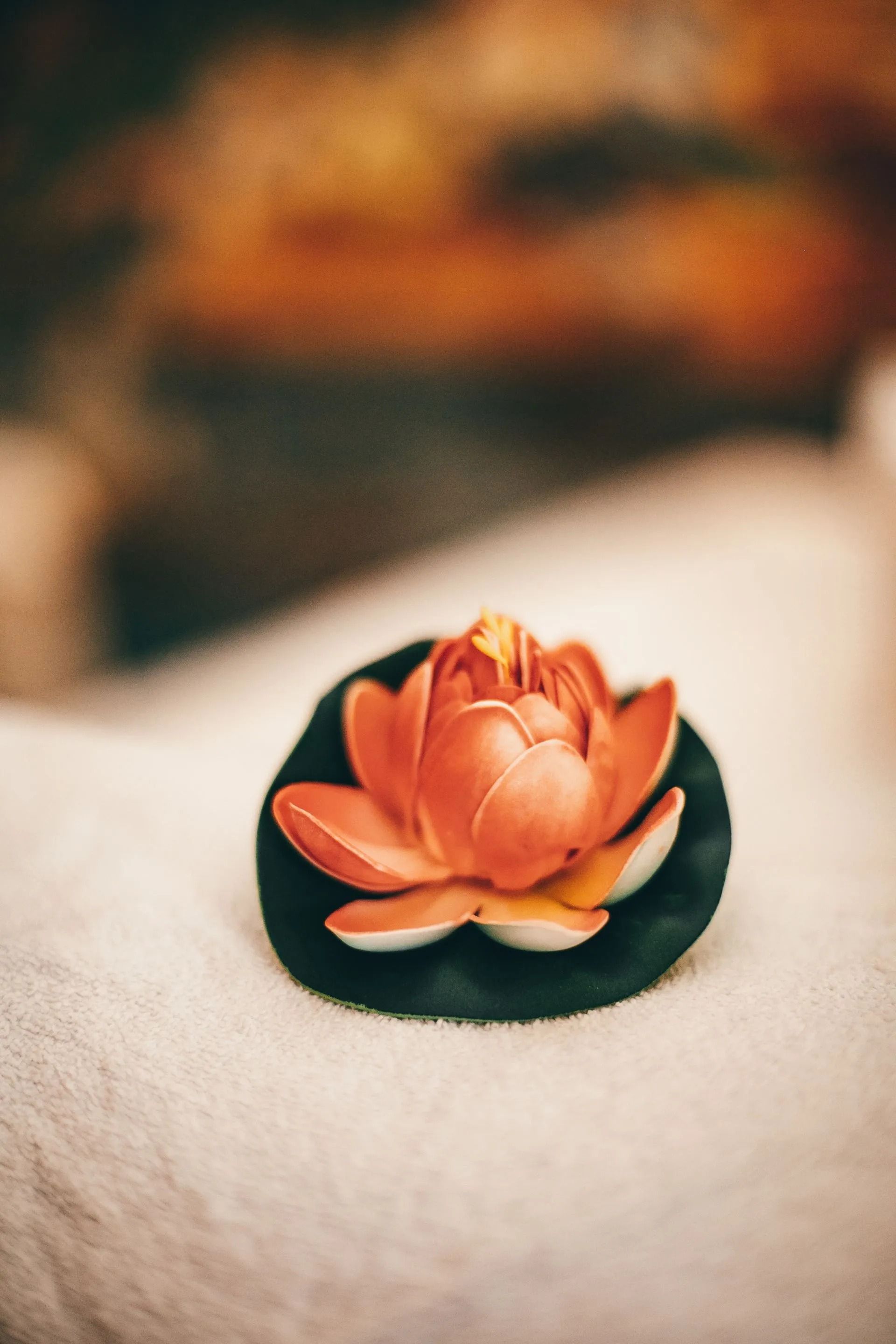 Orange Lotus Flower Soap on a Dark Green Base, Resting on a White Towel — Traditional Massage Services In Broadbeach, QLD
