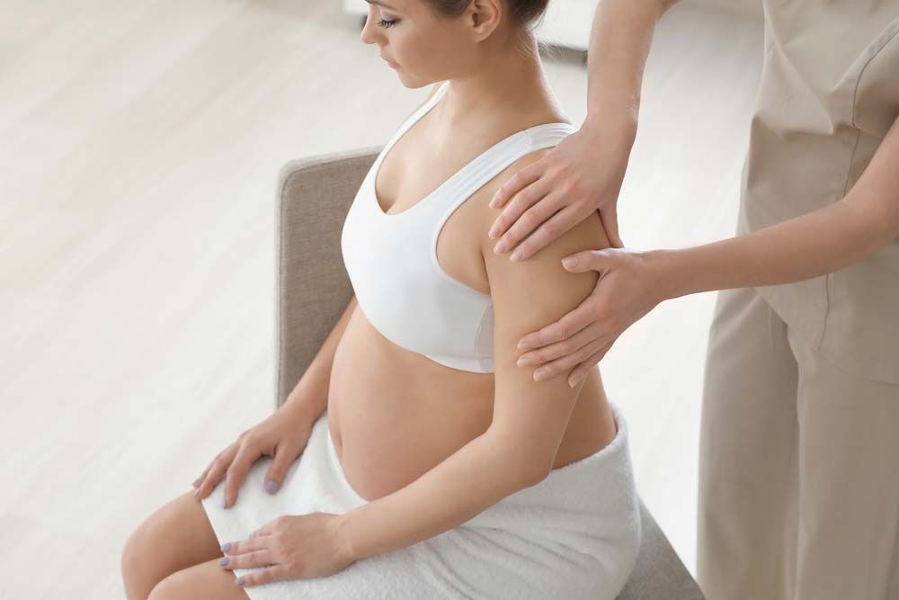 Pregnant Person Receiving Shoulder Massage. Light Setting, Neutral Tones — Traditional Massage Services In Broadbeach, QLD