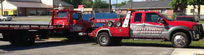 Red and silver tow truck on a road; the truck has the words 