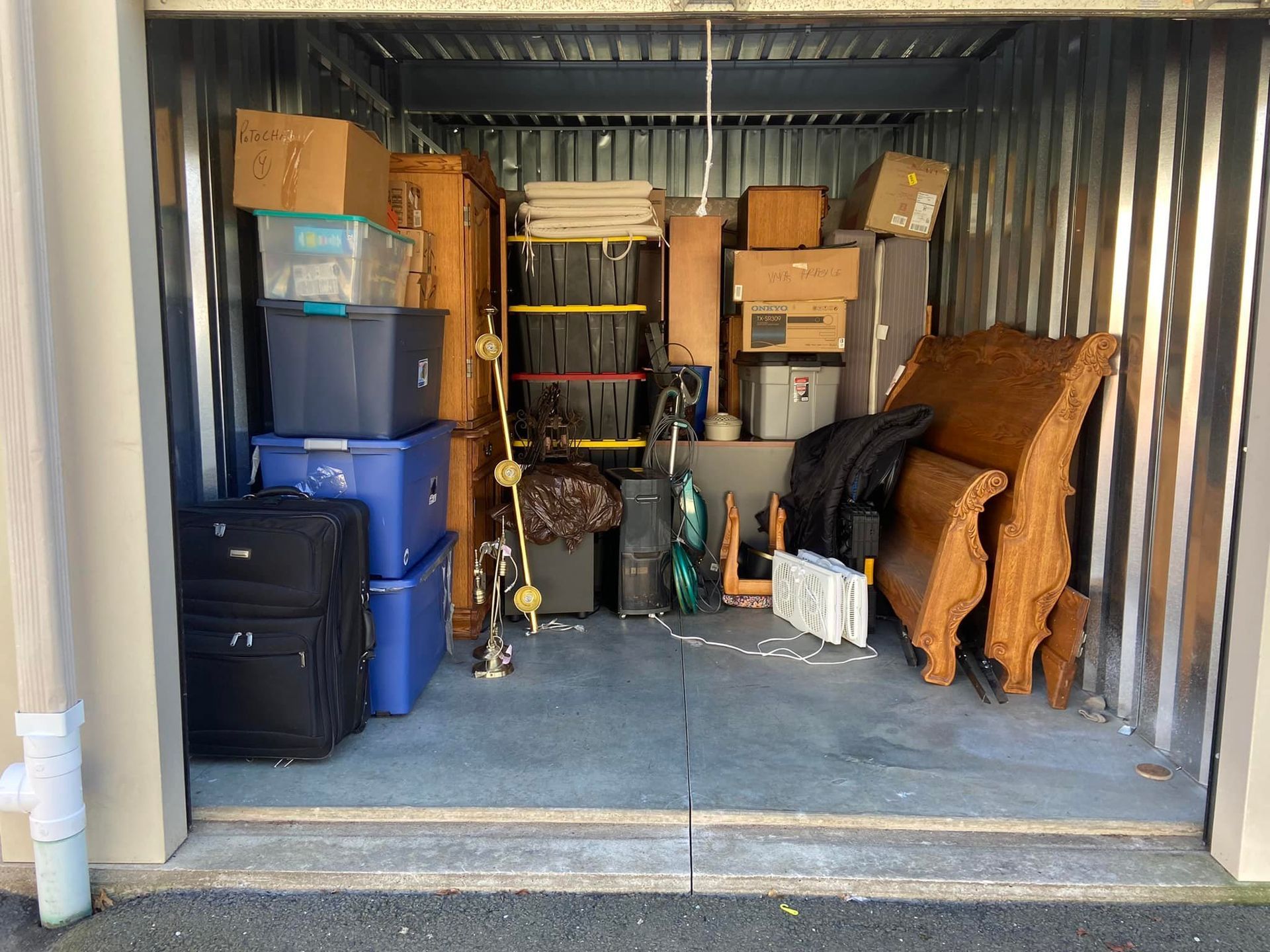 Storage unit packed with furniture, boxes, and luggage.