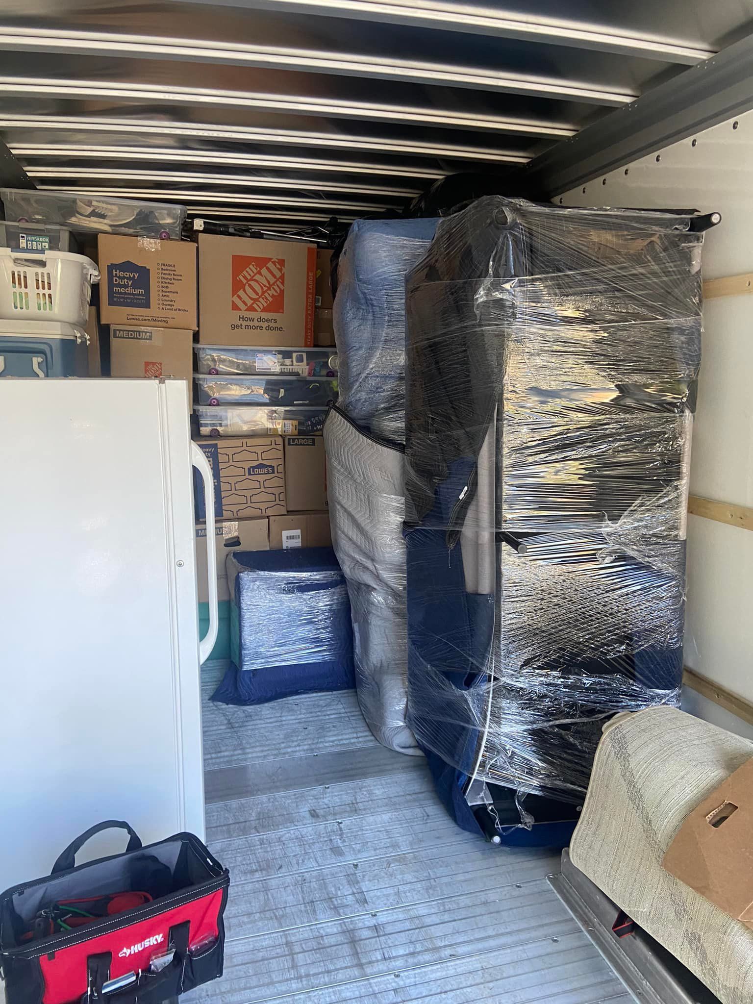 Moving truck interior packed with furniture, boxes, and appliances, ready for transport.