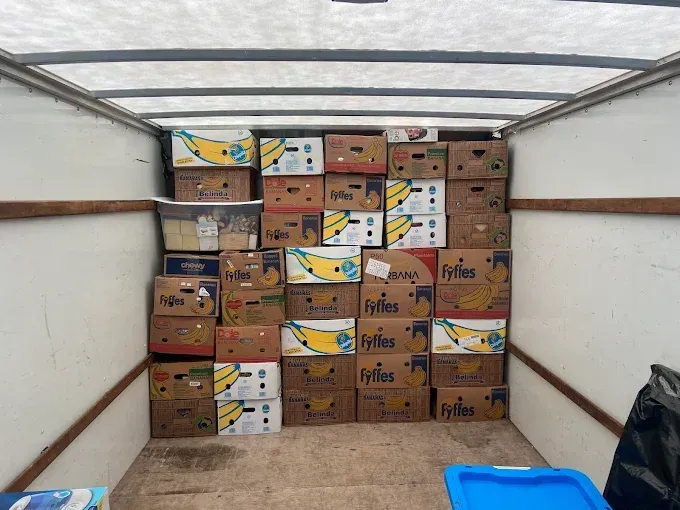 Boxes of bananas and other food items stacked inside a truck.
