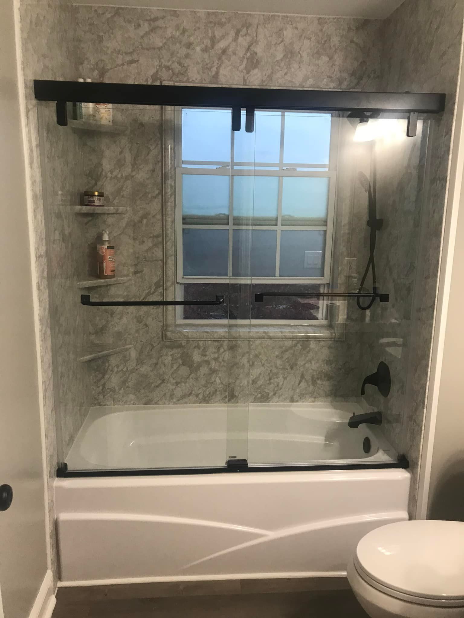 Small bathroom with tub, toilet, and vanity. Beige tiles, light-pink walls, and a small window.