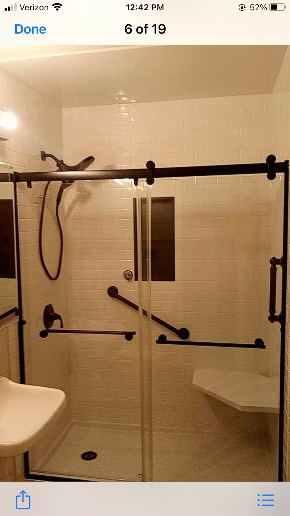 Modern bathroom with a glass shower enclosure, black fixtures, and a white bench.