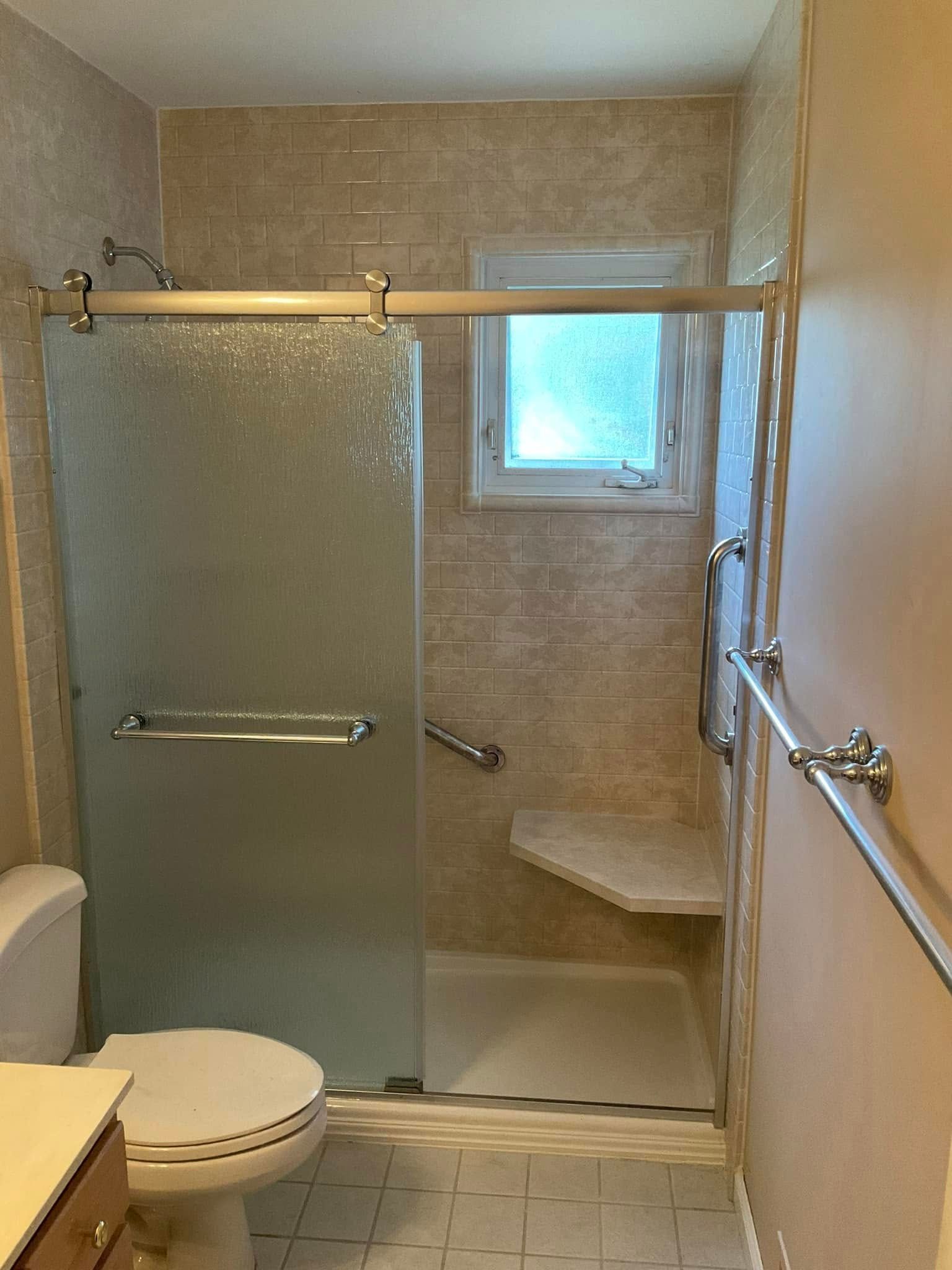 Bathroom with a sliding glass shower door, toilet, and neutral tile.