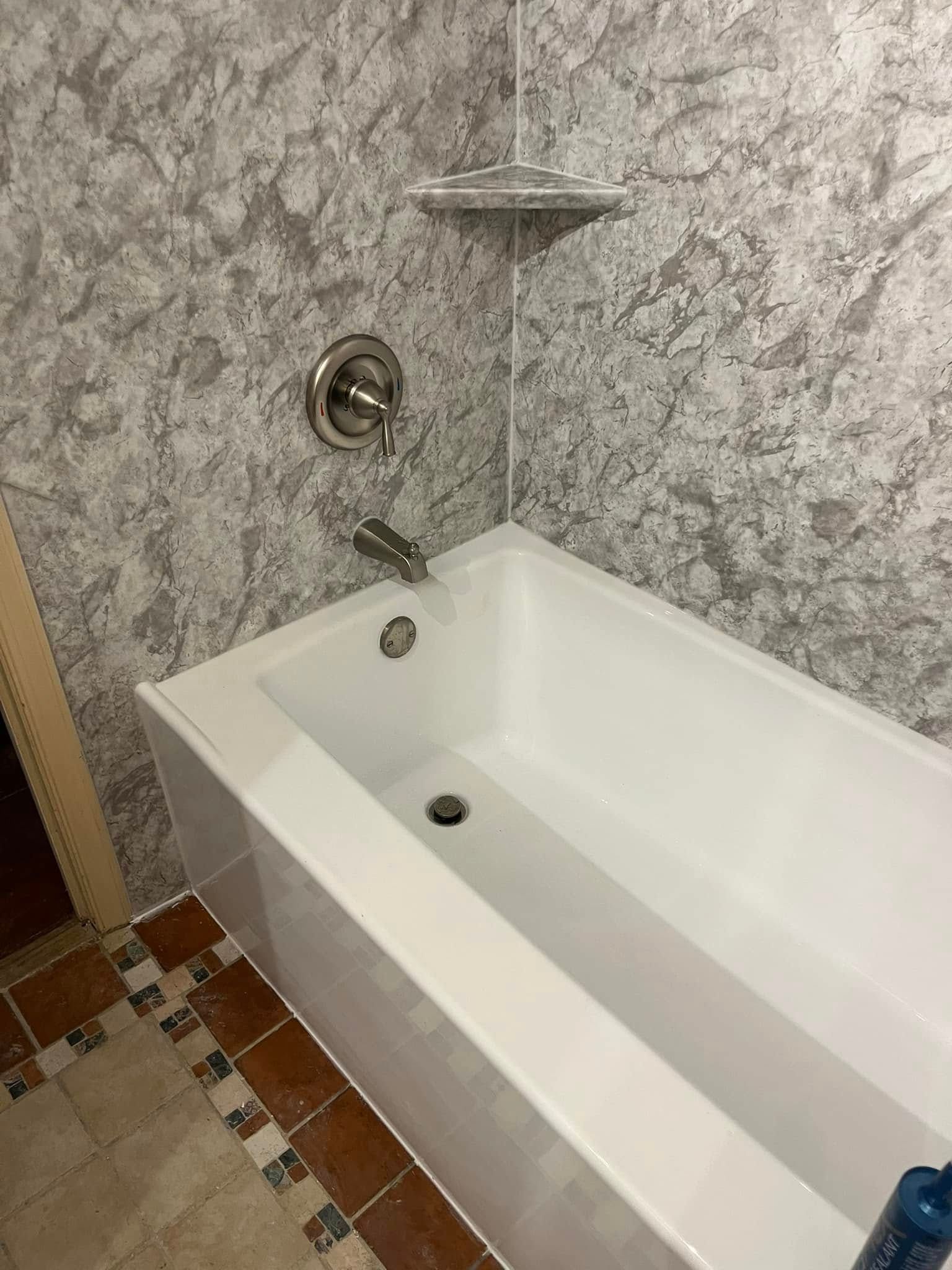 White bathtub with fixtures against a grey patterned wall.