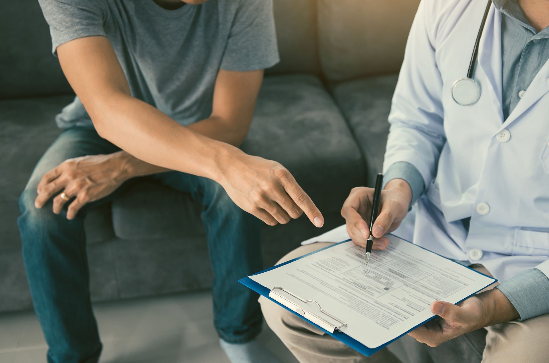 A doctor is talking to a patient who is sitting on a couch.