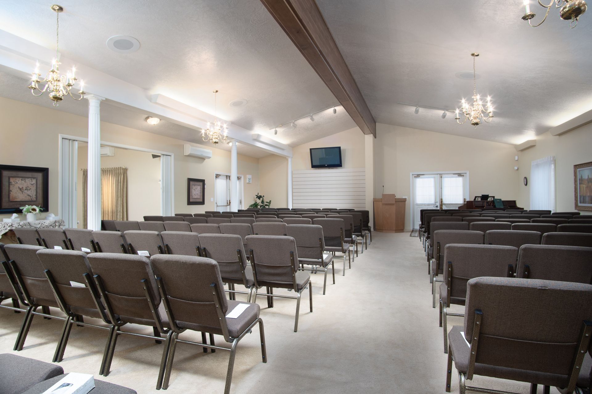 An empty church with rows of chairs and a television on the wall.
