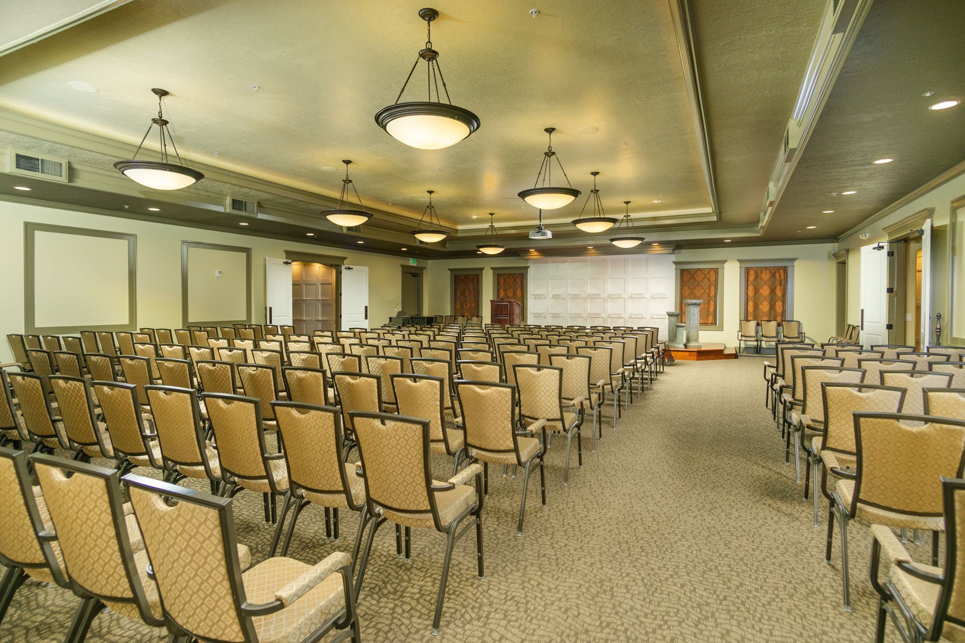 A large room with rows of chairs and a projector screen