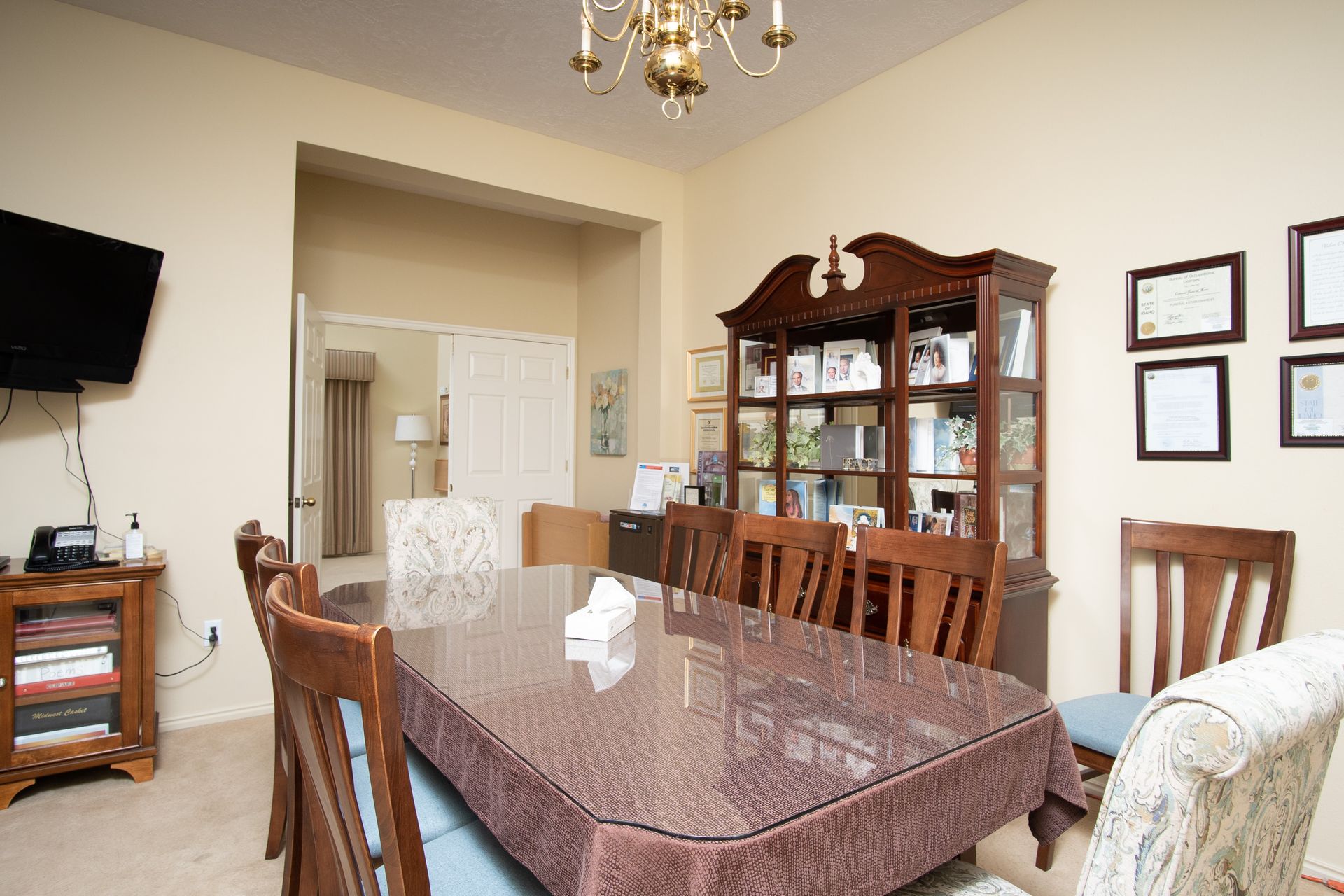 A dining room with a table and chairs and a television.
