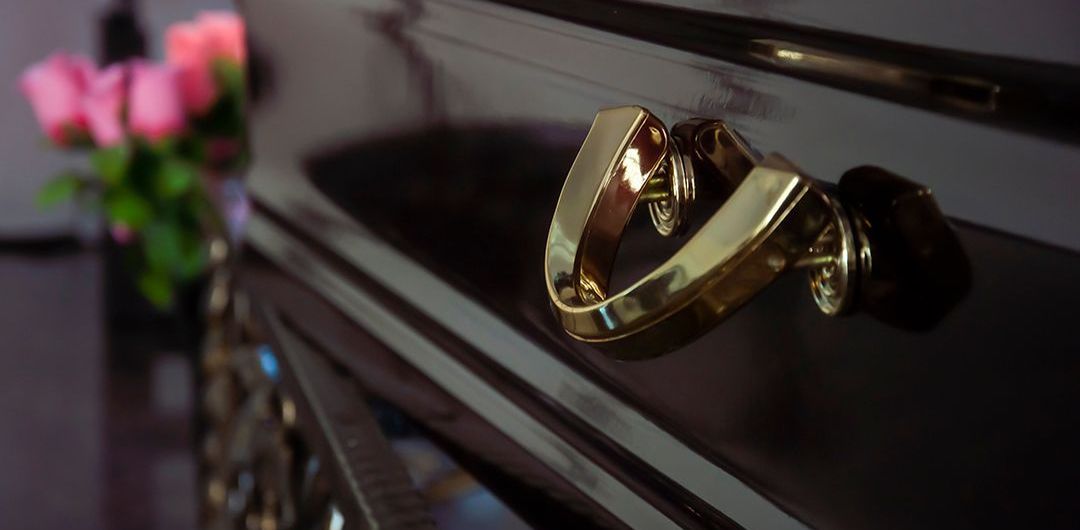 A close up of a gold handle on a black dresser.