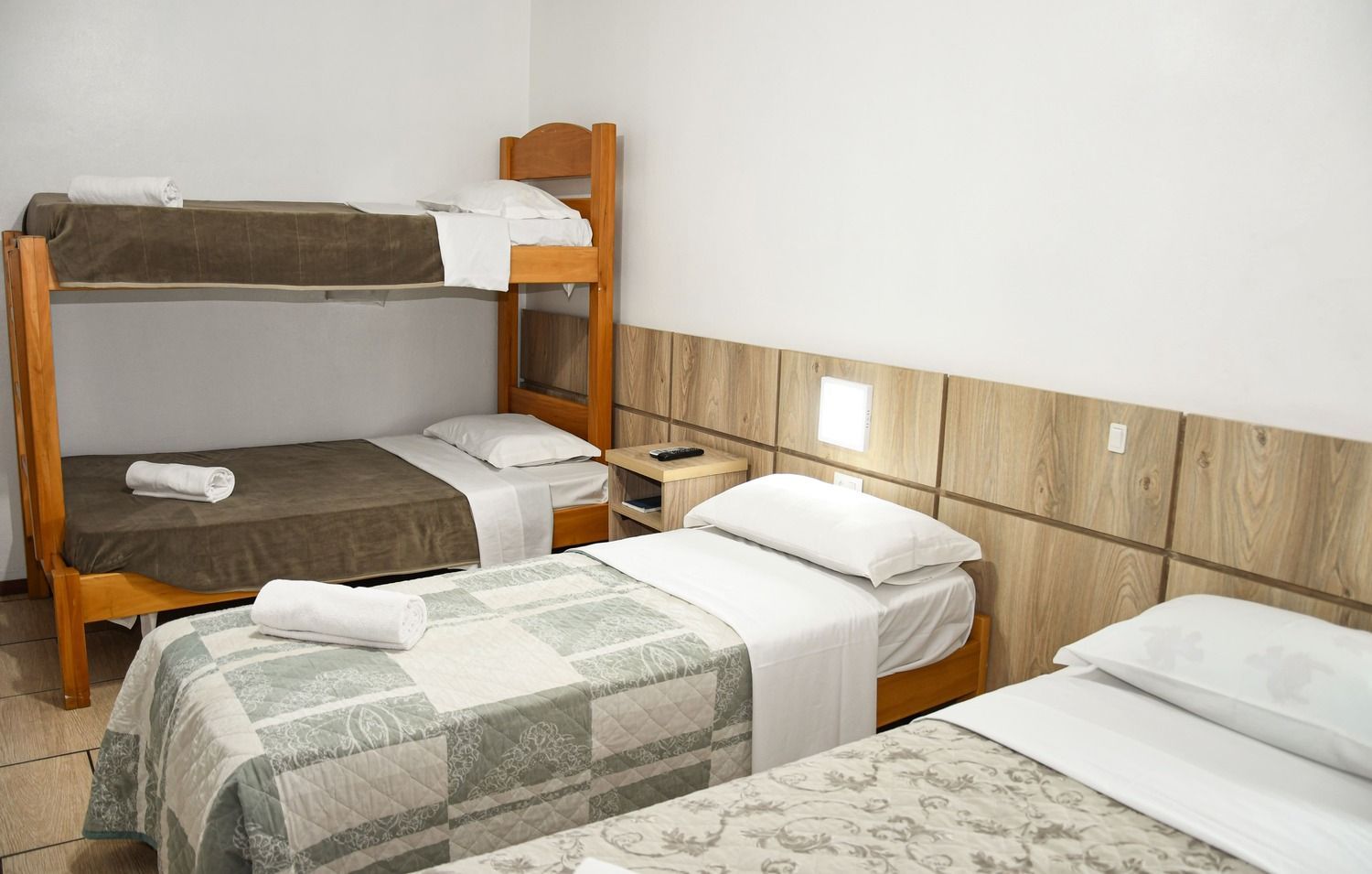 Um quarto de hotel com três camas e dois beliches.