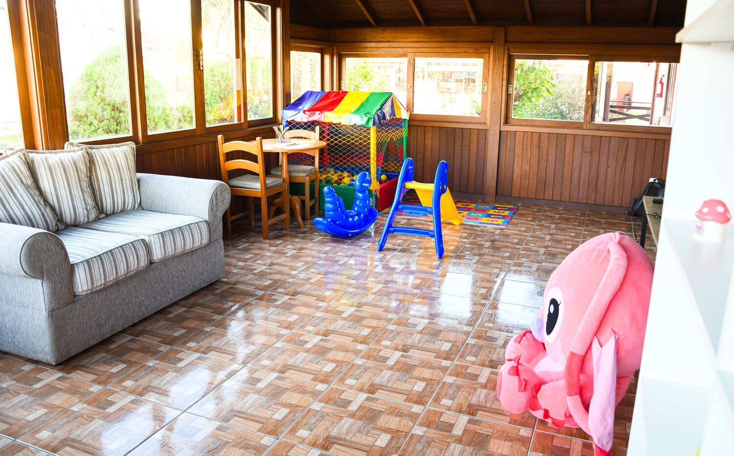 Uma sala de estar com um sofá, cadeiras e um playground.