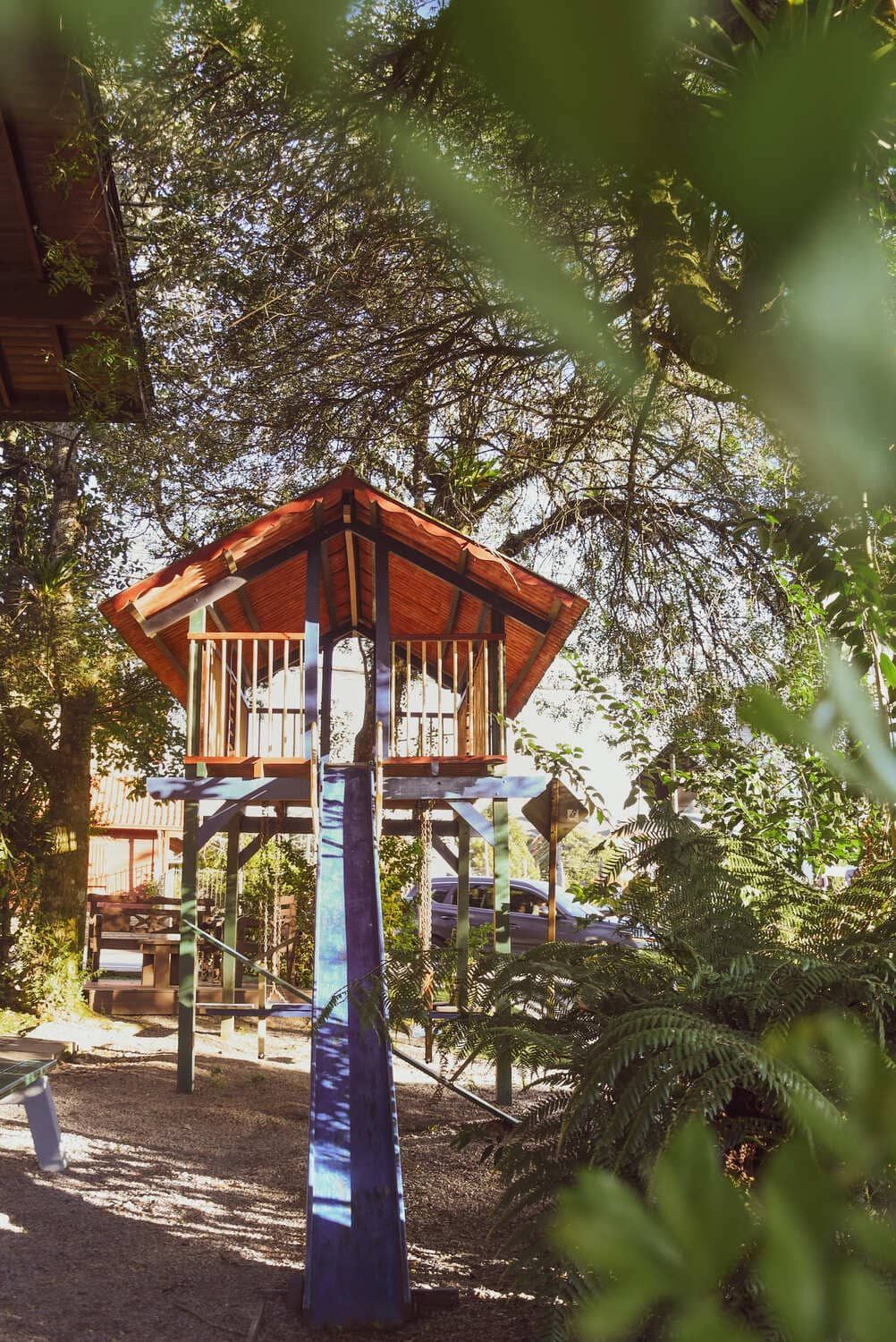 Uma casa na árvore com um escorregador no meio de uma floresta.
