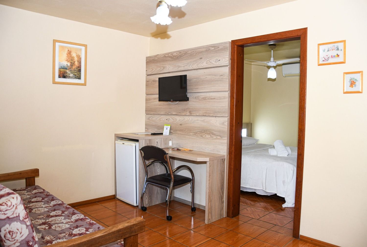 Um quarto de hotel com um sofá, mesa, cadeira e televisão.