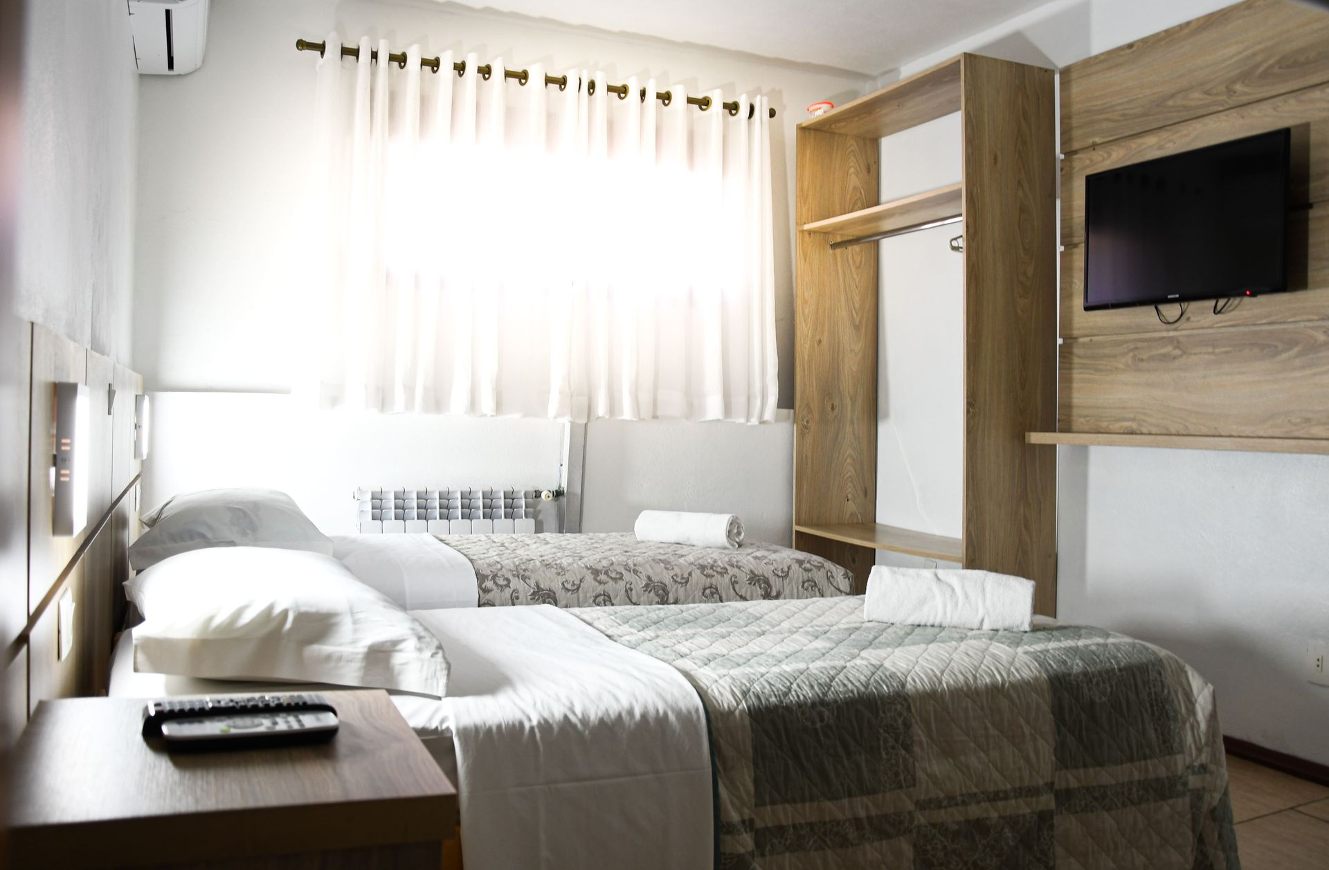 Um quarto de hotel com duas camas e uma TV de tela plana.