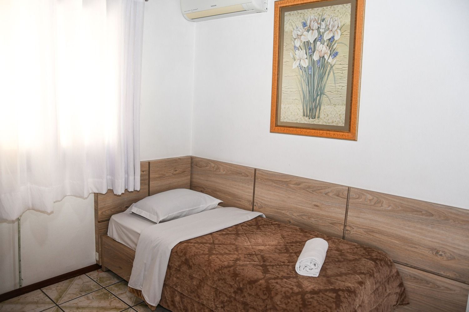 Um quarto com uma cama de solteiro e um quadro na parede.