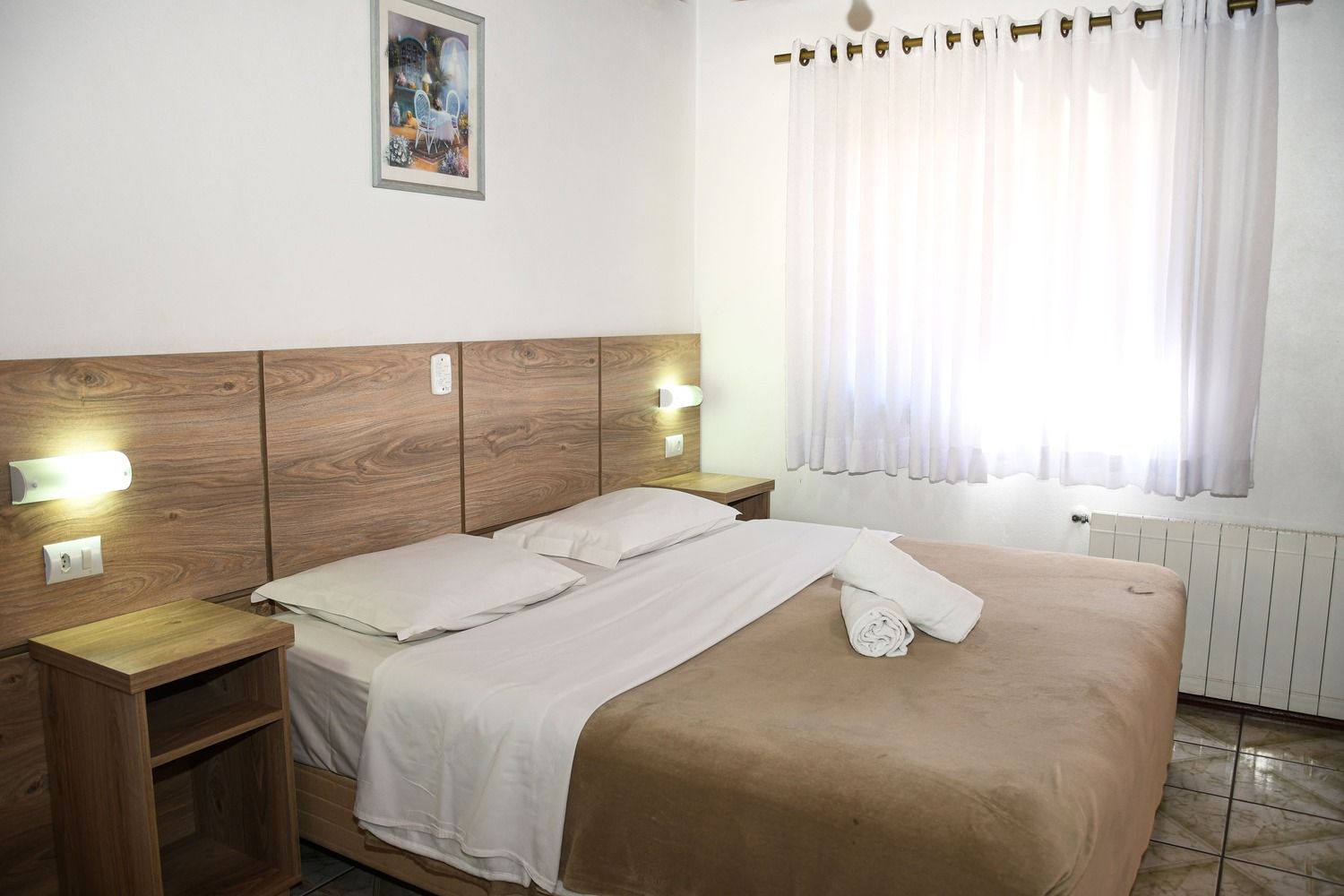 Um quarto de hotel com uma cama, mesas de cabeceira e uma janela.