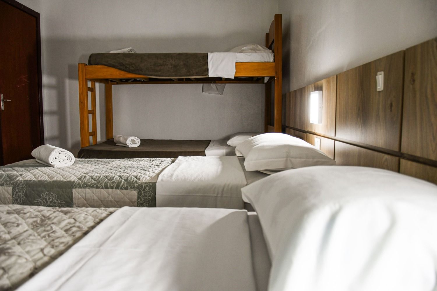 Um quarto com três camas e um beliche.