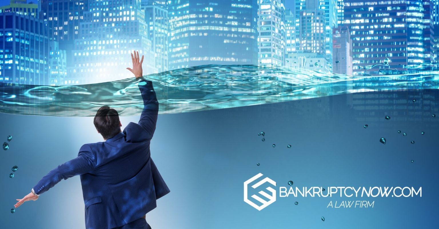 Businessman drowning in water with city underwater; bankruptcy concept.
