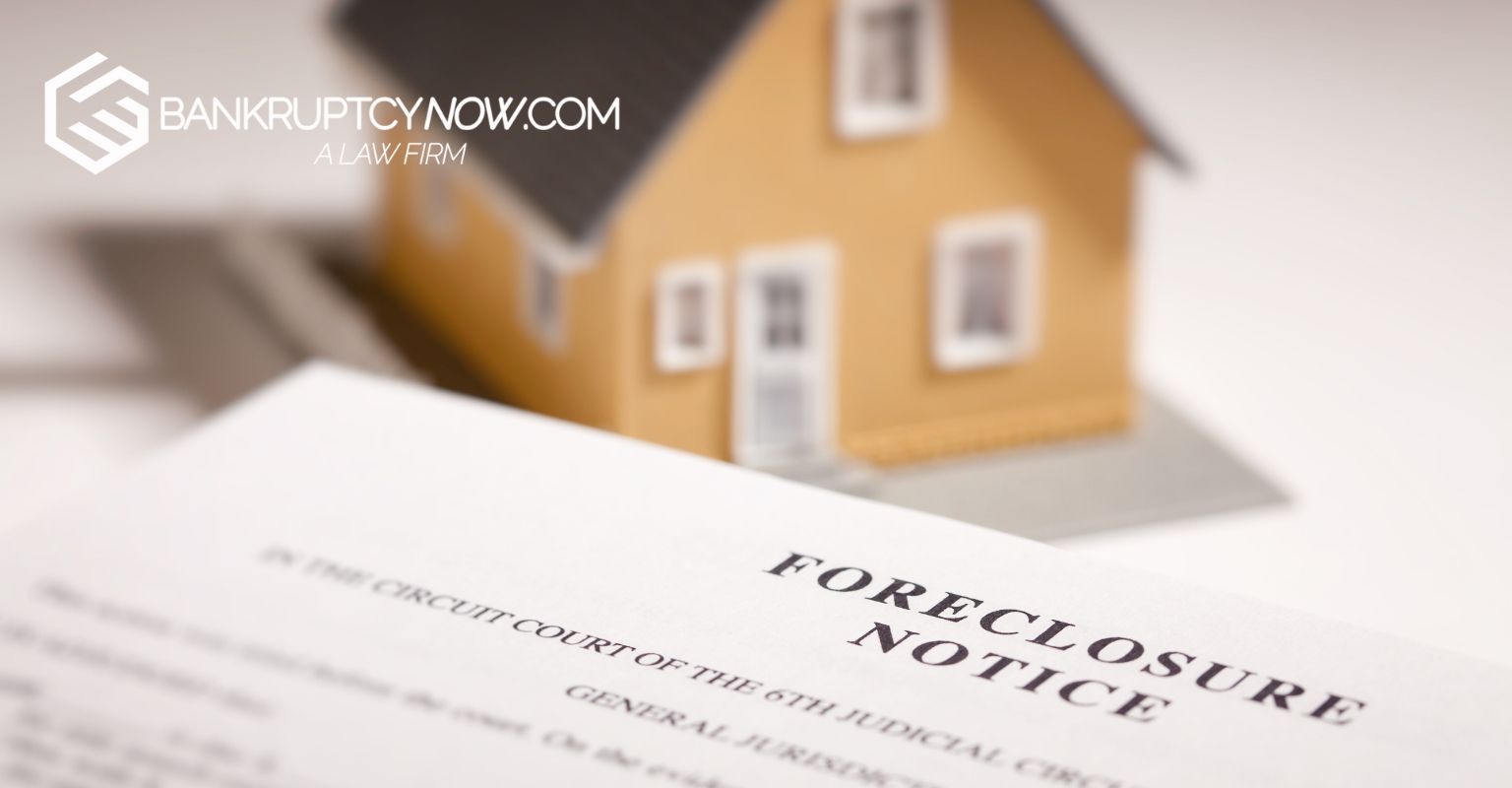 Foreclosure notice in front of a toy house. Paper is slightly blurred.