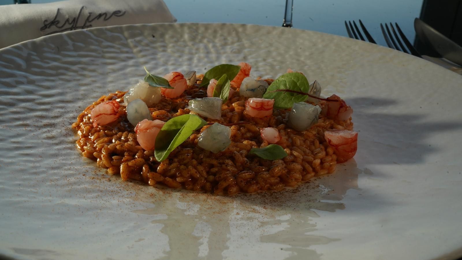 Piatto di risotto rosso con gamberi ed erbe aromatiche.