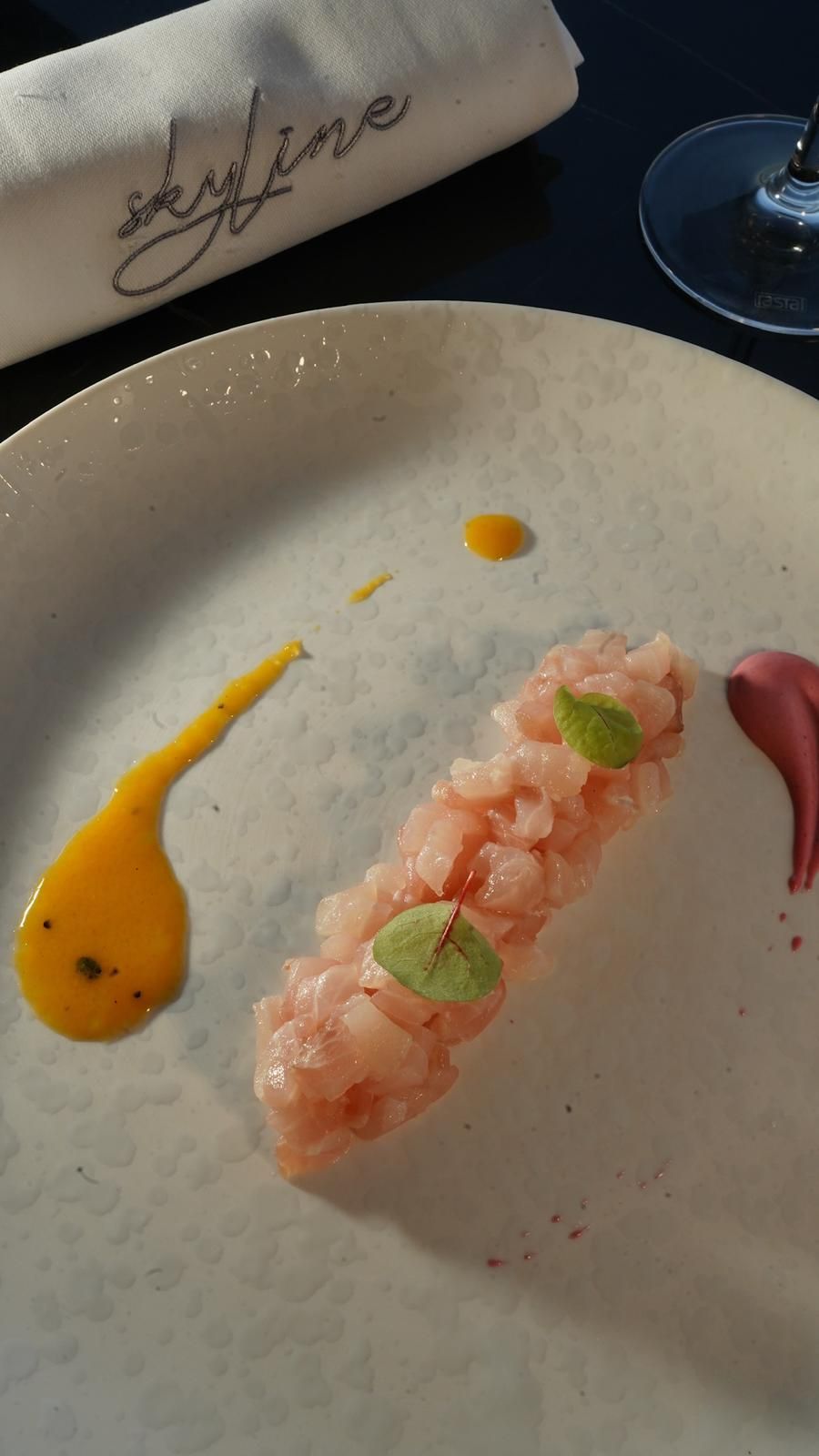 Piatto con frutti di mare crudi, salse gialle e rosse e un tovagliolo con la scritta