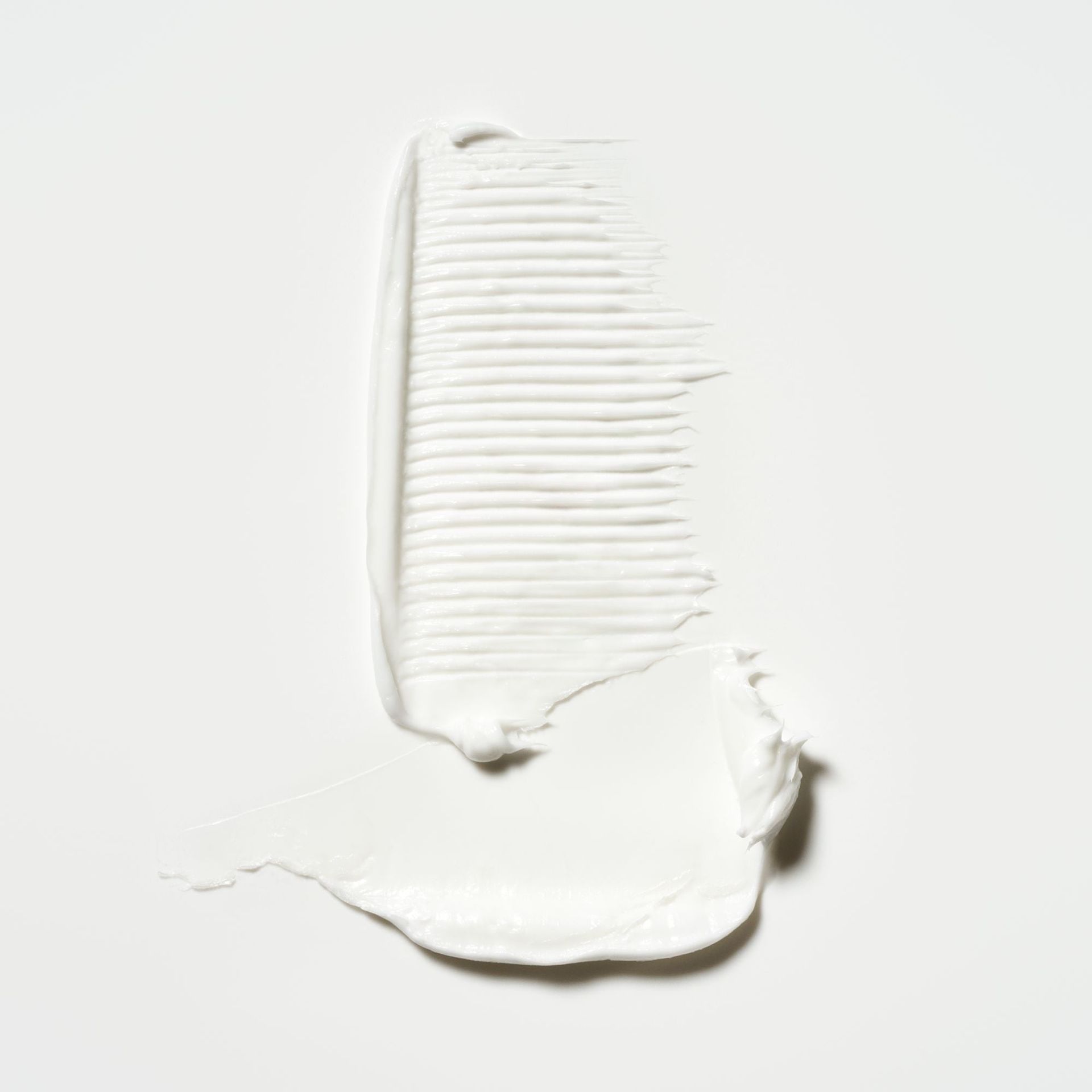 A white, opaque cosmetic cream swatch with a ribbed texture against a plain light background.
