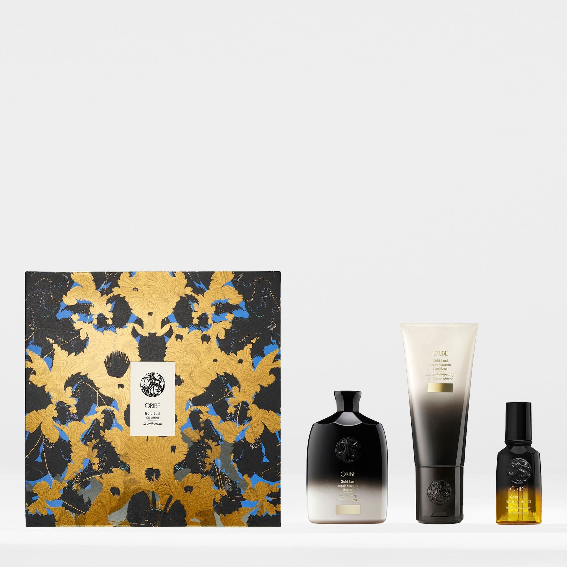 A gift set featuring a decorative black and gold box, a perfume bottle, a tube of cream, and a small oil vial.
