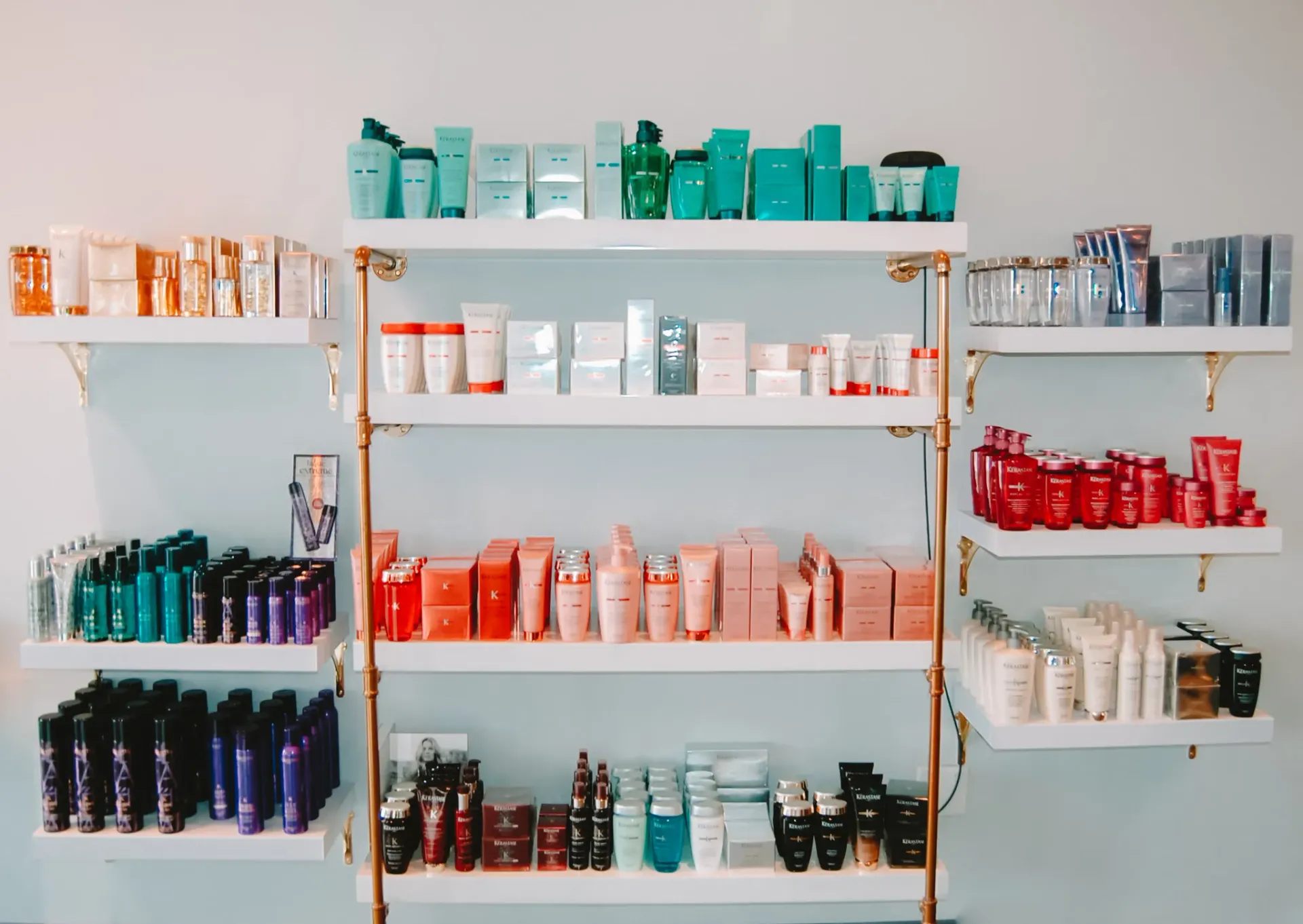 Shelves filled with various skincare and beauty products arranged by color in a brightly lit retail display.