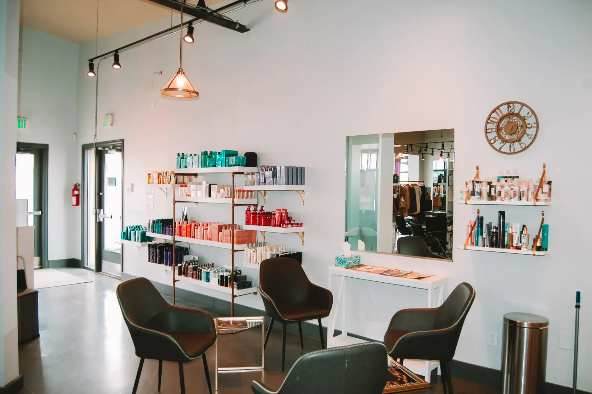A waiting area in a salon with chairs, shelves displaying hair care products, a mirror, and a decorative wall clock.