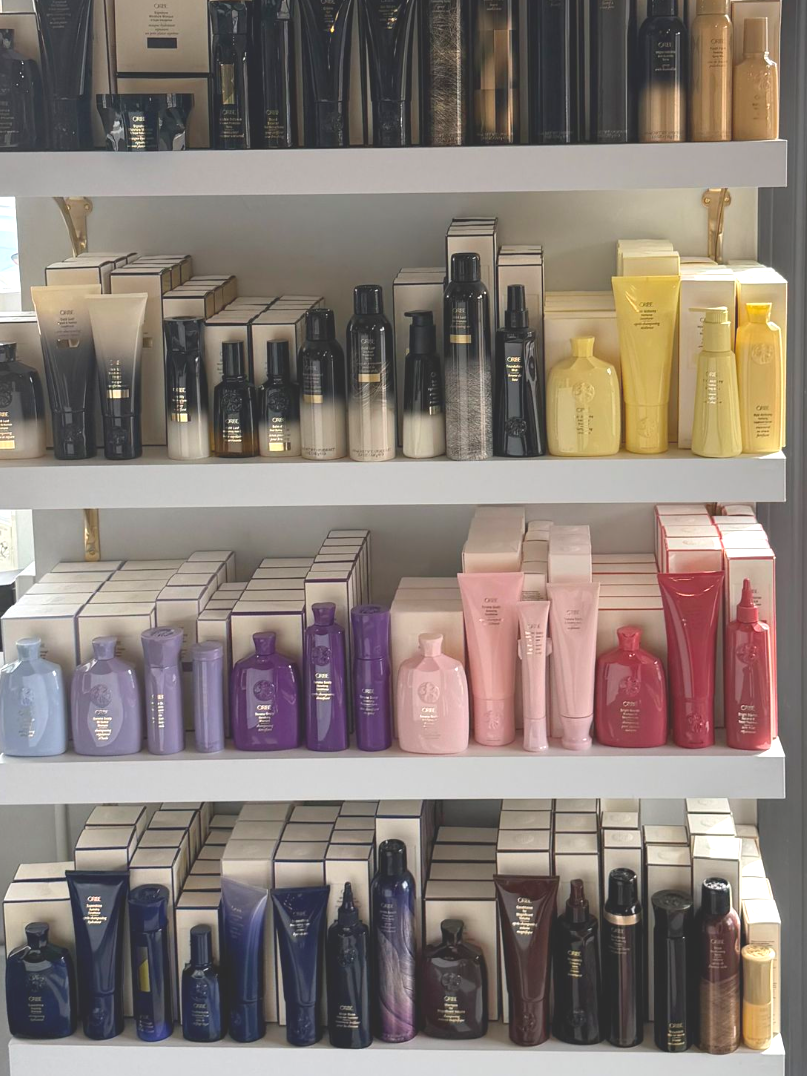 Shelves stocked with rows of various beauty products, arranged by color in a bright, organized display.