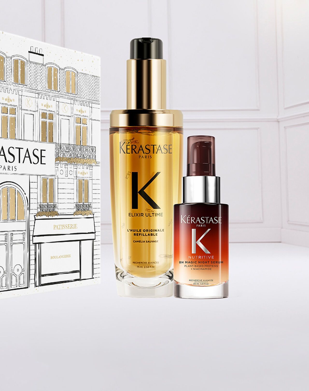 Two Kérastase hair oil bottles with a decorated gift box on a white background.
