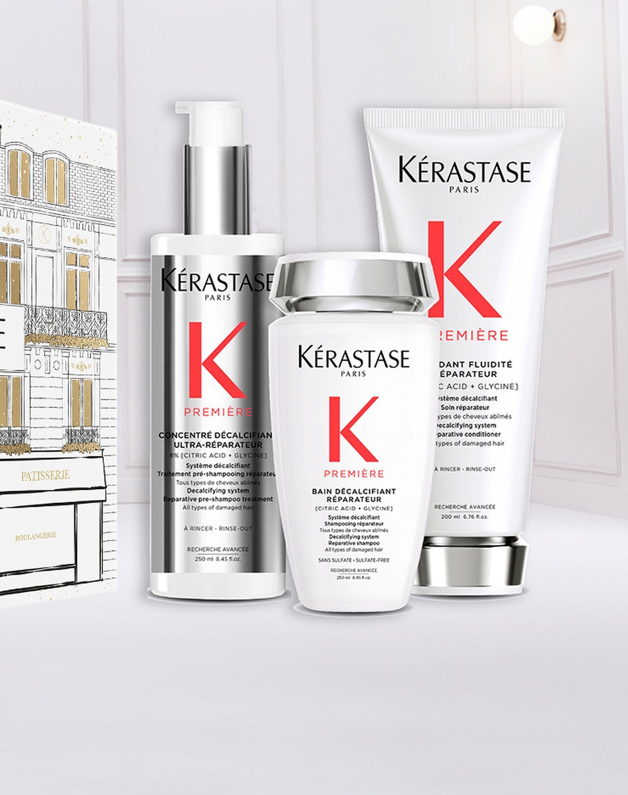 Three Kérastase hair care products, including two bottles and a tube, arranged against a white, minimalist background.