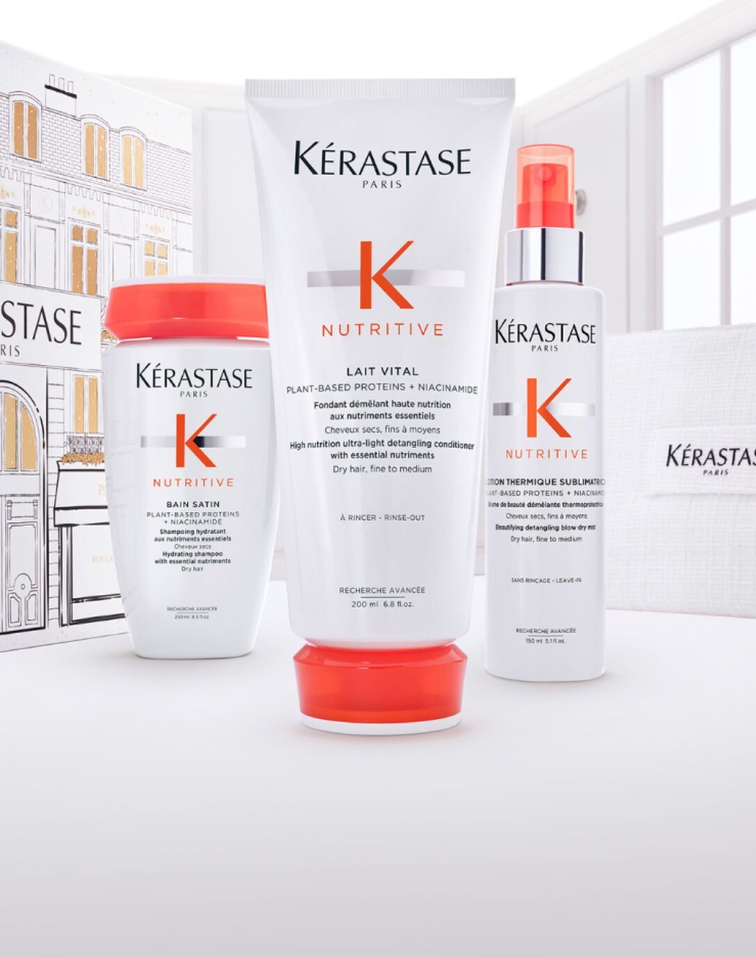 Three Kerastase Nutritive hair care products—a shampoo, conditioner, and spray—arranged on a white surface.