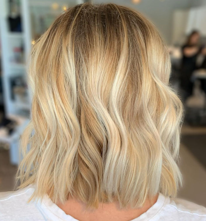 Shoulder-length, wavy blonde hair with highlights in a salon setting.