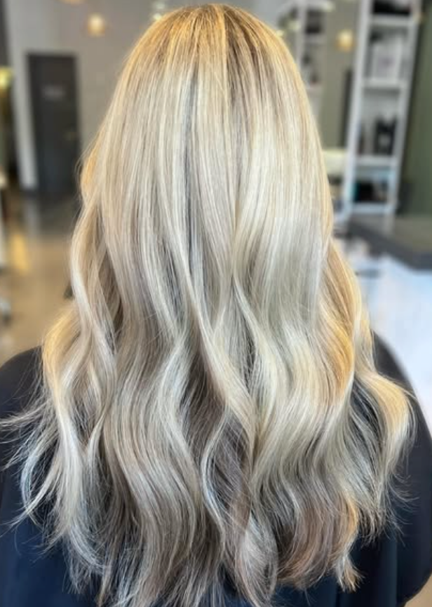 Back view of wavy, highlighted blonde hair in a salon setting.
