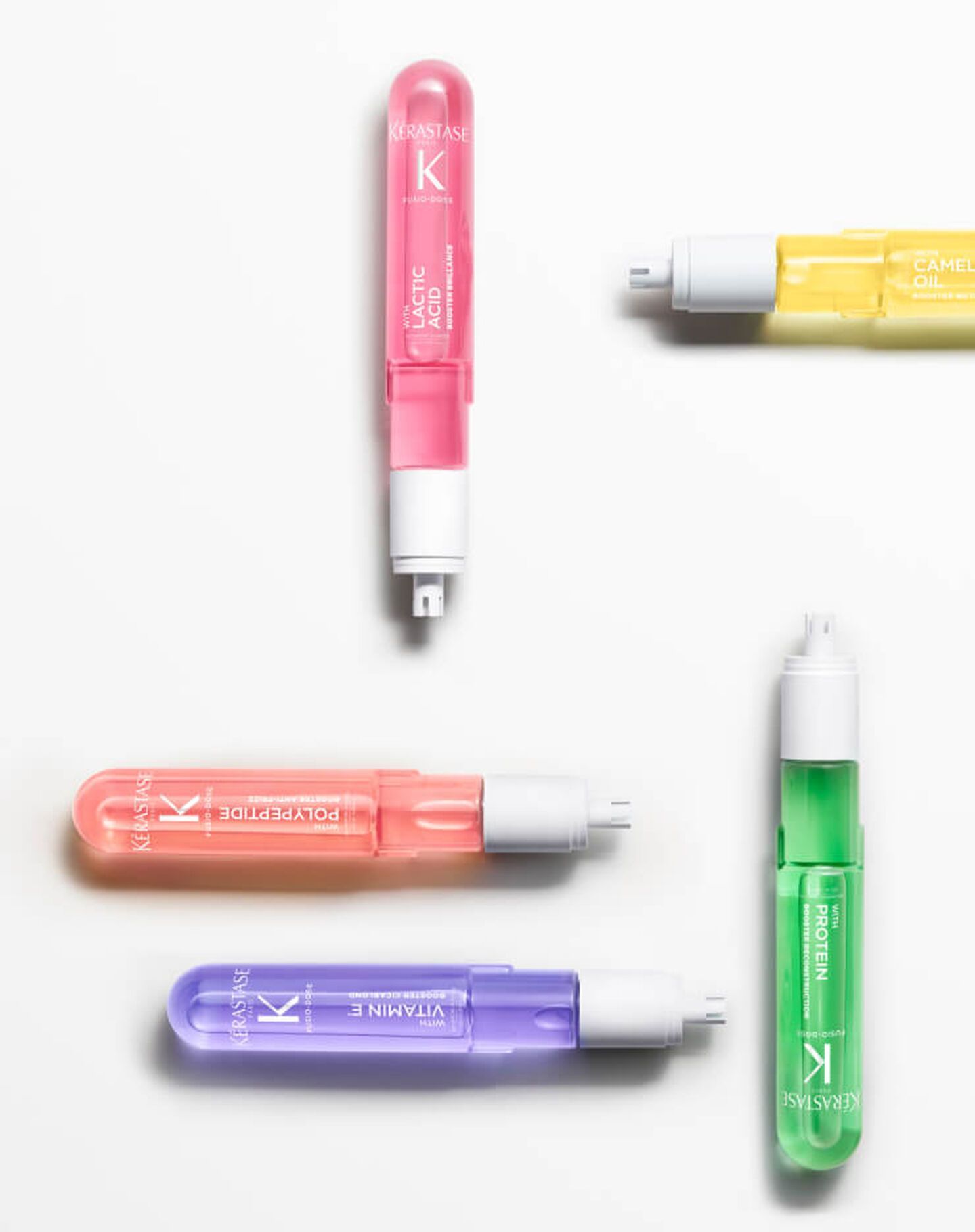 Five colorful, translucent Kérastase ampoules arranged on a white background.