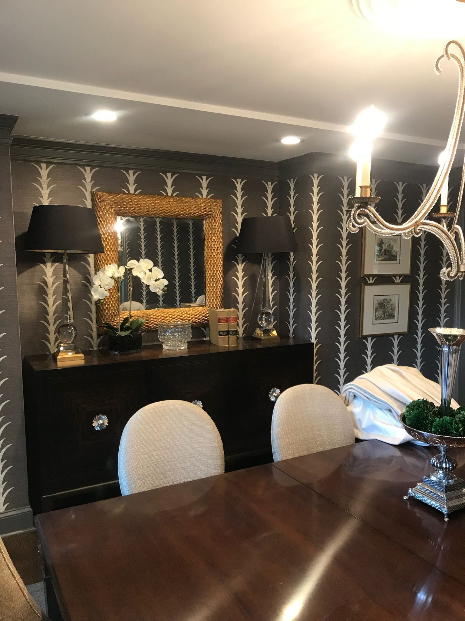 A dining room with a table and chairs and a mirror