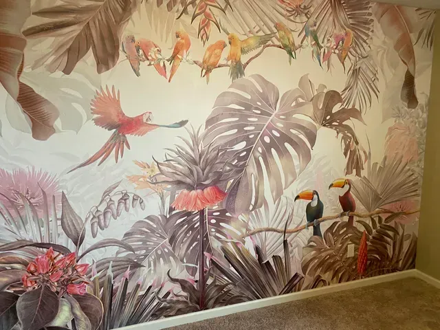A wall with a painting of birds and plants on it.