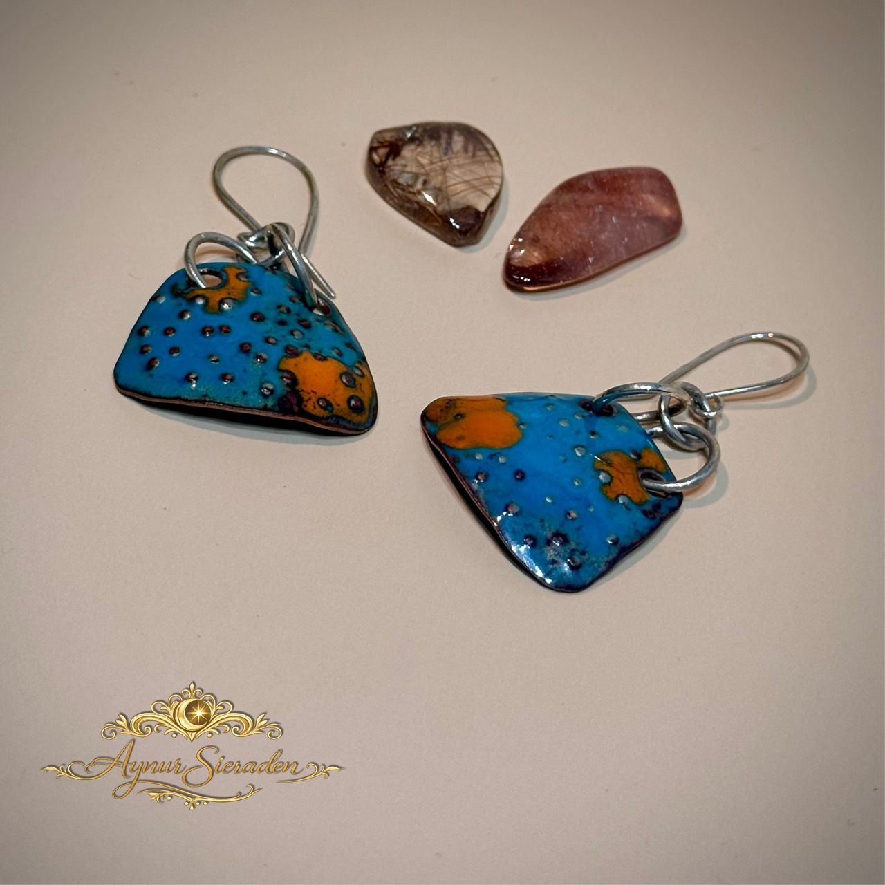 Aynur Sieraden, Uniek, bijzonder & 100% handgemaakt. Deze oorbel is versierd met prachtig blauw en oranje emaille. De basis van het emaille is van koper, het oorhaakjes en de onderdelen zijn gemaakt van 925 sterling zilver.