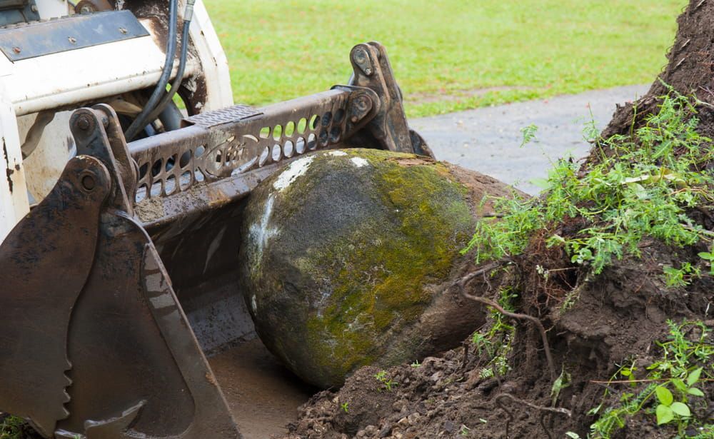 A Large Rock Is Being Moved By A Bulldozer — Brown's Vegetation Management In Mulara, QLD