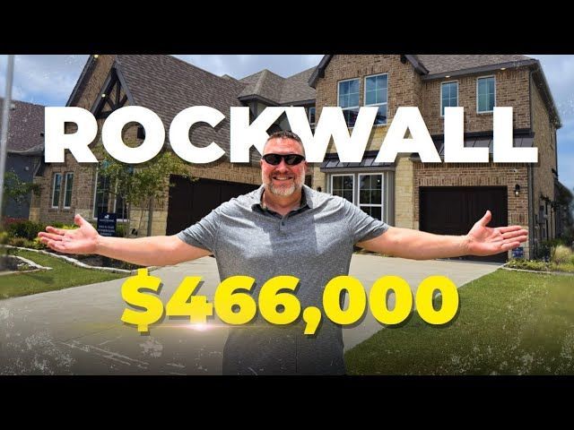 A man is standing in front of a house that is worth $ 466,000