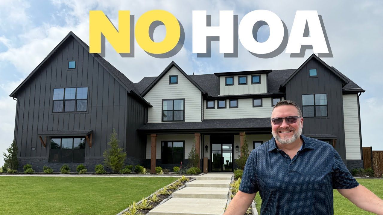 A man is standing in front of a large house.