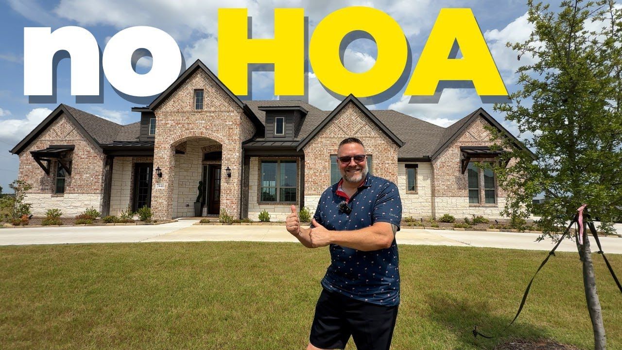 A man is standing in front of a large brick house.