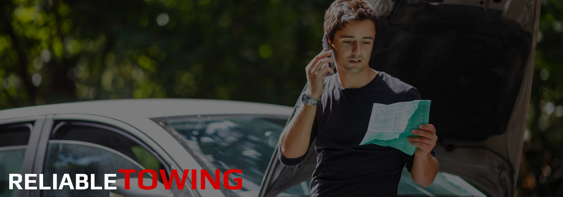 Man on phone, looking at paper by car with open trunk. “Reliable Towing” text.