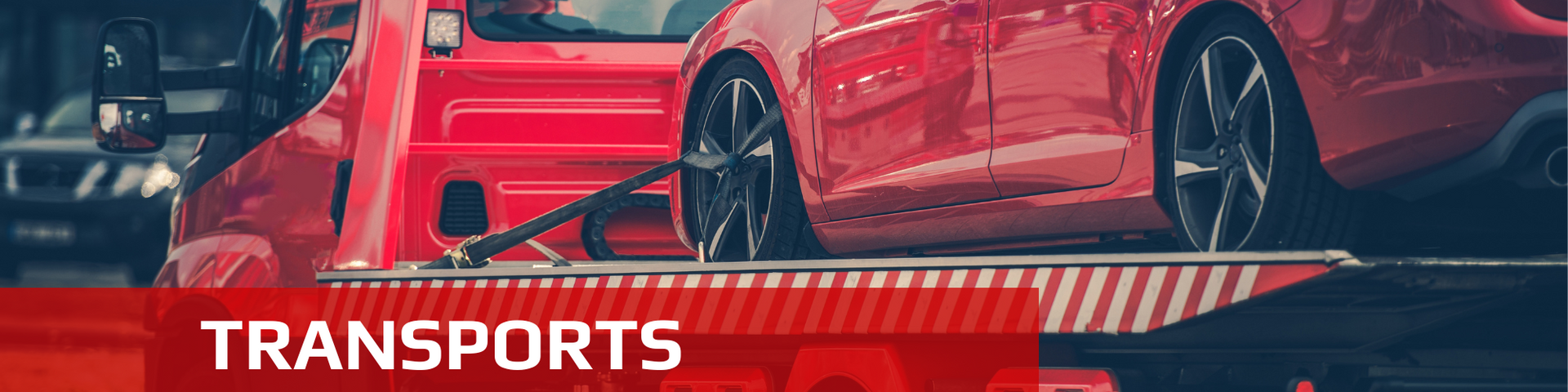 Red car being transported on a flatbed tow truck.