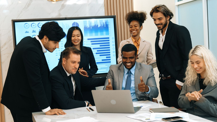 Two people shaking hands in an office, with one person holding a tablet.