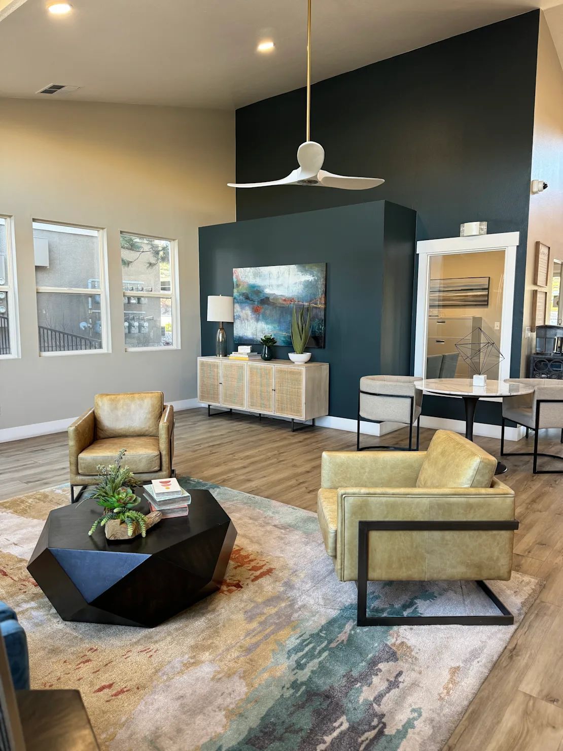 Modern living room with black accent wall, yellow chairs, rug, coffee table, and large windows