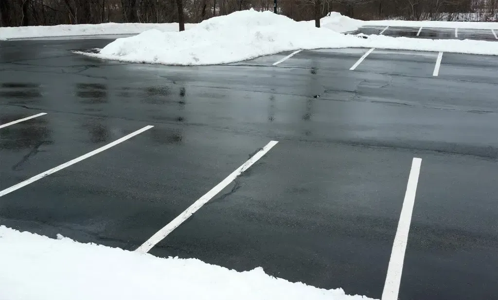 A parking lot with snow on the ground and white lines
